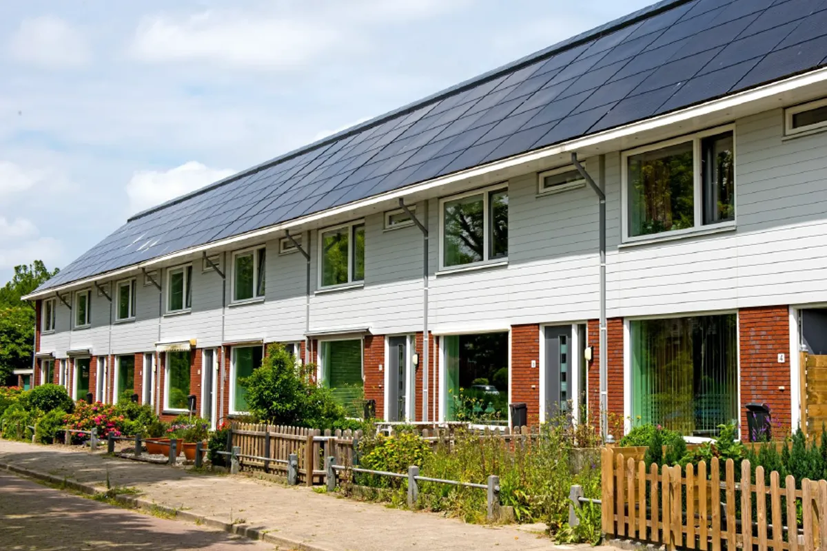 Dakisolatie met zonnepanelen op rijtjeshuizen ter verduurzaming van woningen.